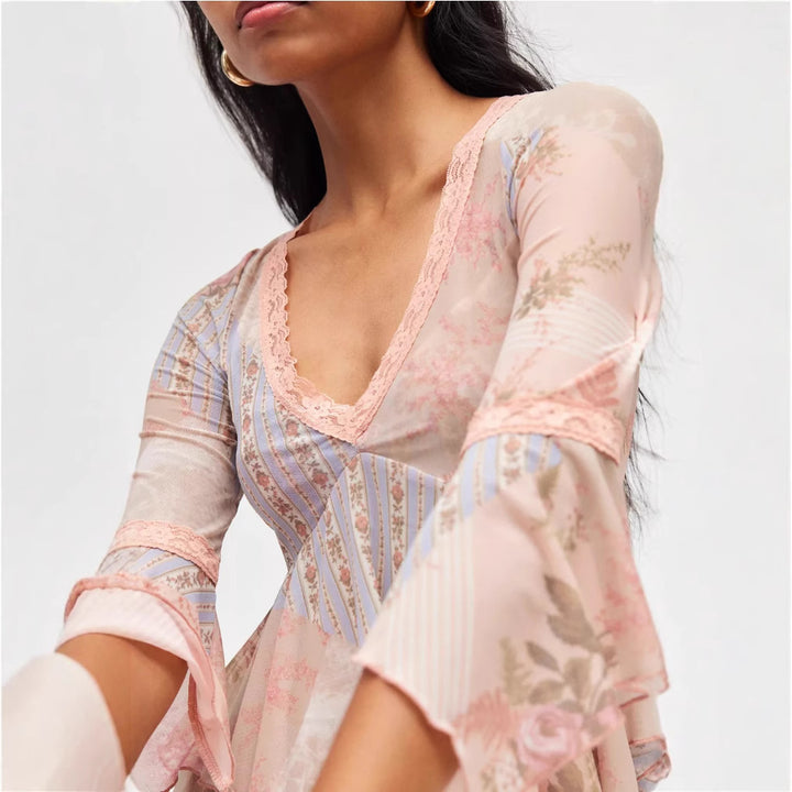 Ladies sheer mesh top with V-neck, lace trim, asymmetric ruffle hem, and bell sleeves StylebySassy