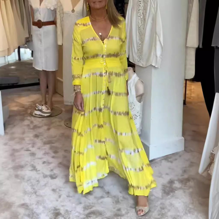 Women's flowing maxi dress with V-neck, full button placket, fitted tassel belt, and pleated skirt StylebySassy