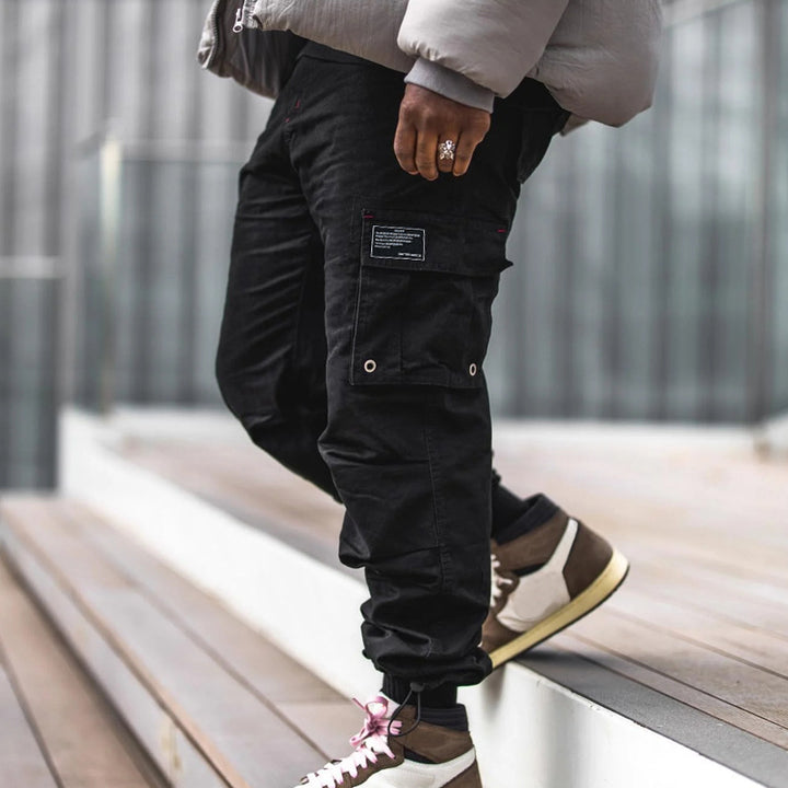 Men's multi-pocket casual trousers made of cotton twill with tapered leg and adjustable ankle drawstring StylebySassy