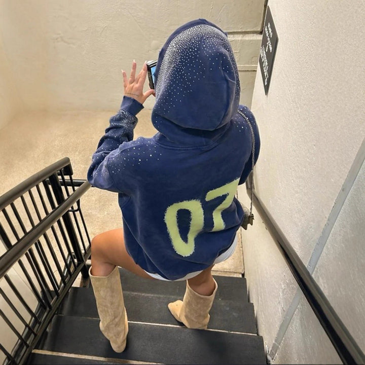 Women's oversized hoodie made of velvet fleece with distinctive logo print, glitter trim, and kangaroo pocket StylebySassy