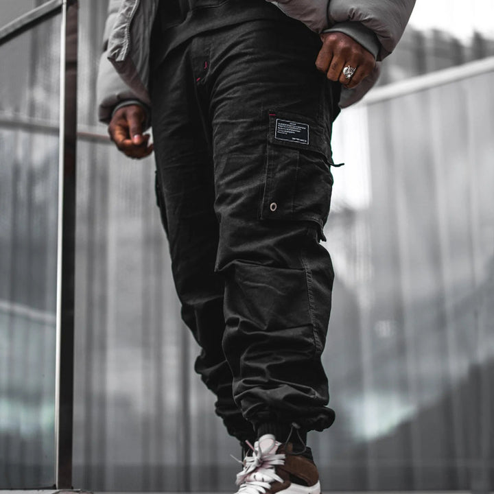 Men's multi-pocket casual trousers made of cotton twill with tapered leg and adjustable ankle drawstring StylebySassy